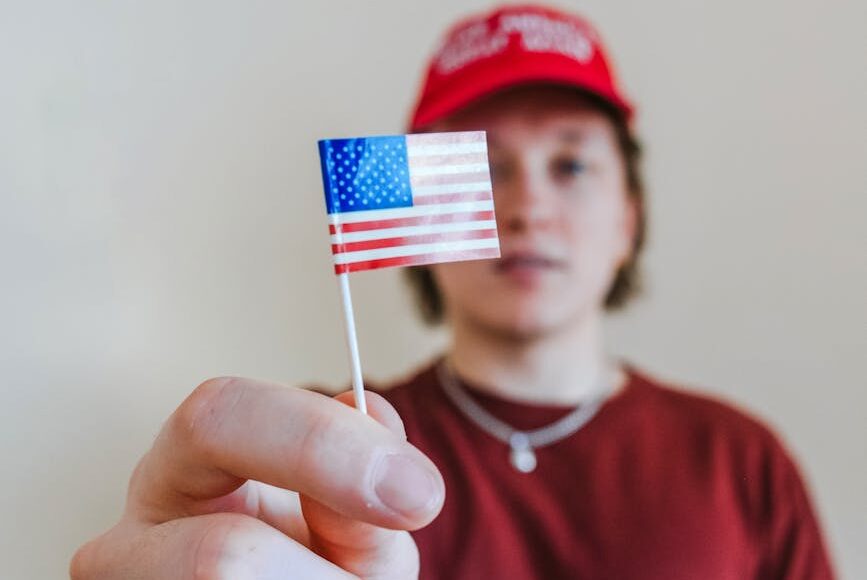 man in red crew neck shirt holding us a flag